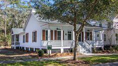 a white house with red shutters on the front porch and stairs leading up to it