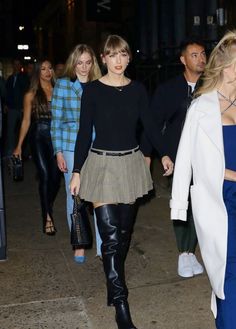 two women are walking down the street with one woman in black and white coat, another wearing blue