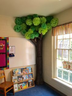 a classroom with a tree on the wall and several children's bookshelves