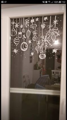 a window decorated with christmas ornaments and baubies hanging from it's side