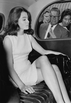 black and white photograph of woman sitting on seat in airplane with man looking out window