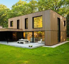 a modern house in the middle of a lush green field with trees and grass around it