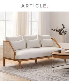 a white couch sitting on top of a wooden table in a living room next to a window