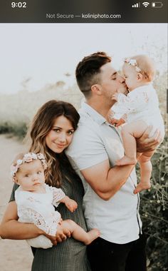 a man and woman holding two babys in their arms