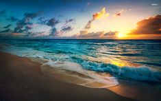 the sun is setting over the ocean with waves crashing on the beach and clouds in the sky