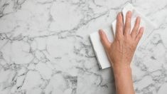 a person's hand on a cleaning cloth next to a white marble counter top