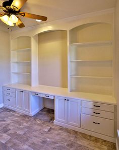 an empty room with white cabinets and a ceiling fan