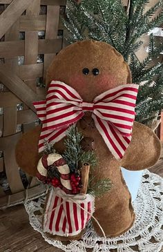 a gingerbread man is holding a basket with christmas decorations on it and standing next to a tree