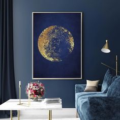 a living room with blue walls and a gold moon painting on the wall above it