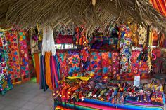 a store with lots of colorful items on display in front of the window and thatched roof