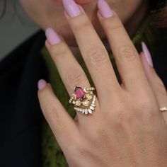 a close up of a person's hand with a ring on her finger and pink nails