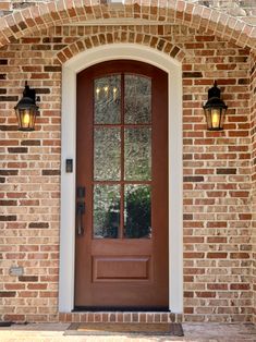 a red brick door with two lights on each side and a white frame around it