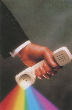 a hand holding a speaker with a rainbow light coming out of it's side