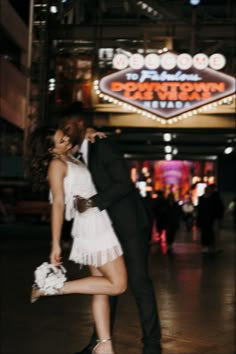 a man and woman posing in front of the las vegas sign