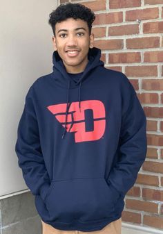 a young man standing in front of a brick wall wearing a sweatshirt with the letter d on it