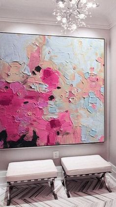 two white benches sitting in front of a large painting on the wall with pink and blue colors