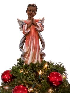 an angel figurine on top of a christmas tree with red baubies