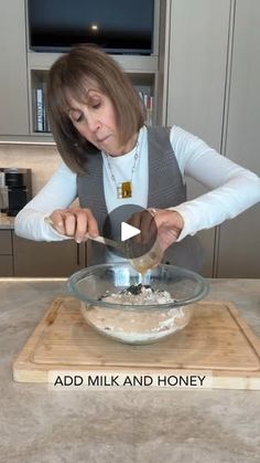 a woman mixing ingredients in a bowl on top of a wooden cutting board with the words add milk and honey