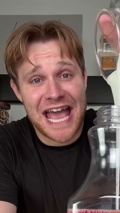 a man holding up a beakle with liquid in it and smiling at the camera