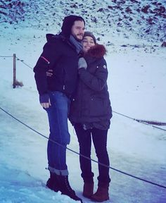 a man and woman are standing in the snow