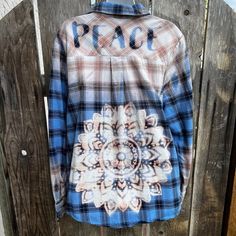 a blue and brown plaid shirt hanging on a wooden fence