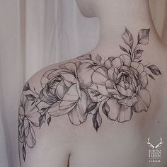 the back of a woman's shoulder with flowers on it and leaves around her