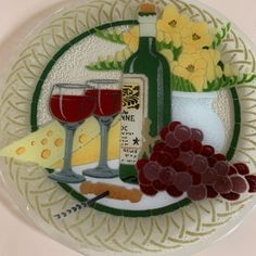 a plate with wine, cheese and grapes on it next to a vase filled with flowers