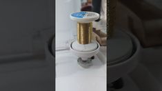 a spool of gold thread sitting on top of a toilet