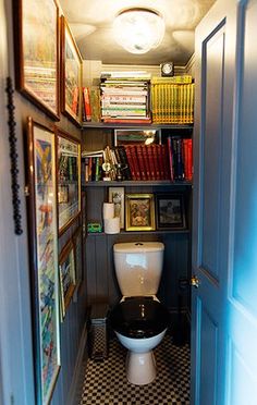 there is a toilet in the corner of this small room with books on the shelves