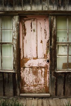 an old wooden door with glass panes on the side of it and grass in front of it