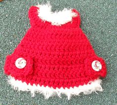 a red and white crocheted hat with buttons on the side sitting on carpet