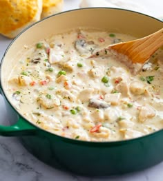 a wooden spoon in a green pot filled with chicken and rice soup next to cornbreads