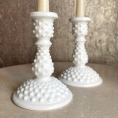 two white candlesticks sitting on top of a table