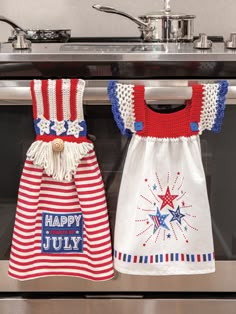 two red, white and blue patriotic aprons hanging from the oven