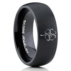 a black wedding ring with an engraved flower on the center and white lettering that reads, so