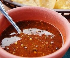 a bowl of chili with tortilla chips in the background