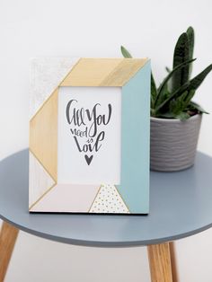 a small wooden frame sitting on top of a table next to a potted plant