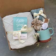 an open box with some items in it on the floor next to a blanket and coffee mug