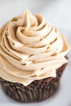 a cupcake with frosting sitting on top of a white plate