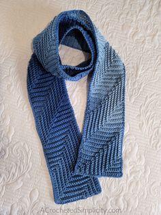 a blue knitted scarf sitting on top of a bed