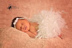 a newborn baby is sleeping with white feathers