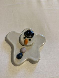 a ceramic snowman ornament on a white sheet