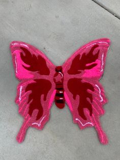 a pink and red butterfly sitting on the ground