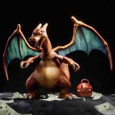 a toy dragon sitting on top of a pile of money with it's wings open