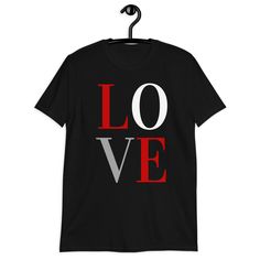 Love Sign Short Sleeve Softstyle Unisex Tee.EXCLUSIVE OF DESIGN. MADE-TO-ORDER. All you need is love. Right? Remember that sentiment every time you wear this inspirational tee. Spread love instead of hate and be the change you wish to see in the world. You will also appreciate just how soft and comfy this 100% ring-spun cotton top is. The double stitching on the neckline, sleeves and bottom hem plus shoulder-to-shoulder taping add more durability and help to ensure you keep this top for a very l Black T-shirt With Heart Graphic For Valentine's Day, Black Short Sleeve T-shirt For Valentine's Day, Valentine's Day Black T-shirt With Text Print, Black Slogan T-shirt For Valentine's Day, Black Graphic Tee For Valentine's Day, Valentine's Day Black Slogan T-shirt, Valentine's Day Black T-shirt With Slogan, Black Graphic Print Top For Valentine's Day, Charitable Giving