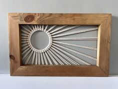 a wooden frame with string art in the shape of a sunburst on it