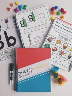 three notebooks with letters and numbers on them next to markers, pens and pencils