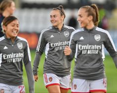 two female soccer players are laughing together on the field