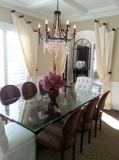 a dining room table with chairs and a chandelier hanging from it's ceiling