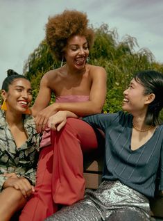 three women sitting on a bench laughing together